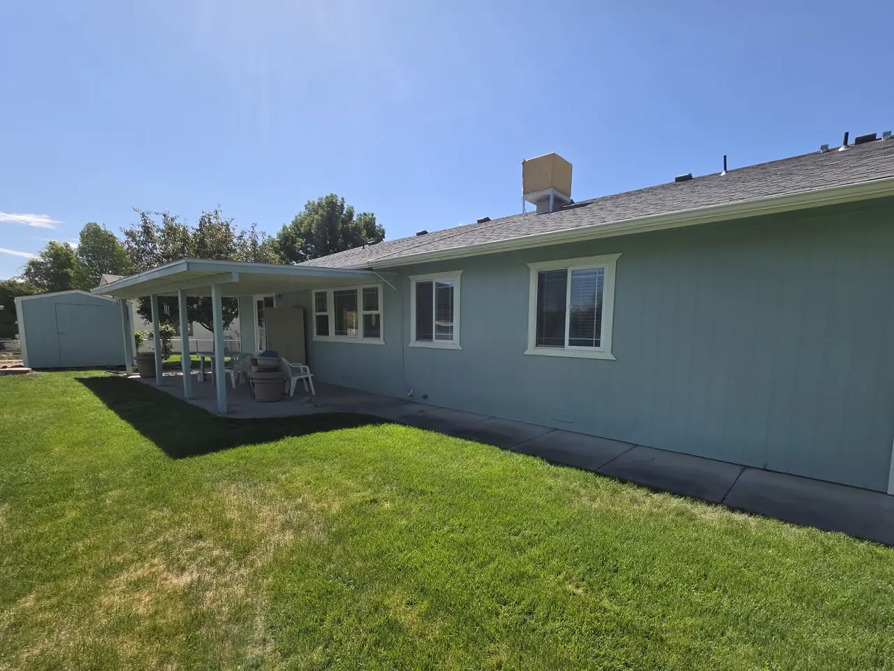 Rear of a light blue home with white trim and covered patio