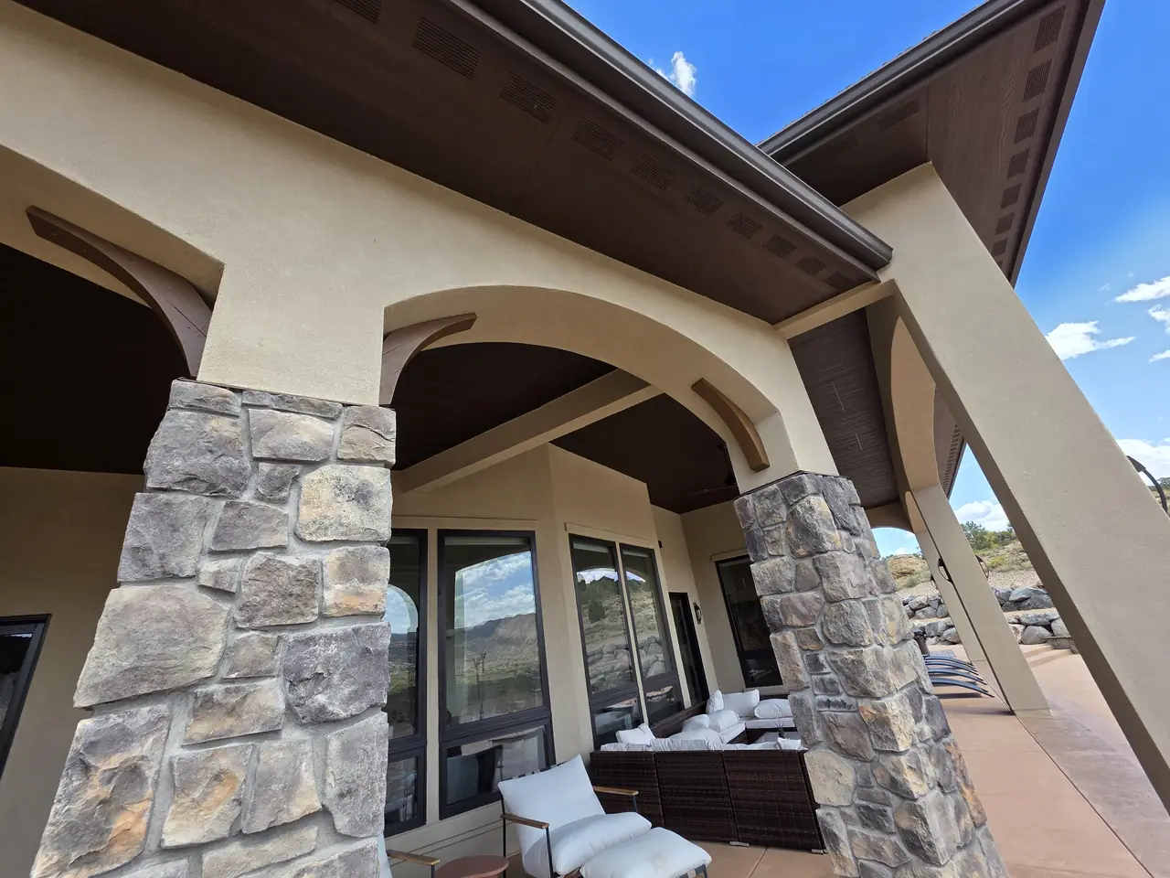 Covered porch with stone columns and freshly stained wood ceiling